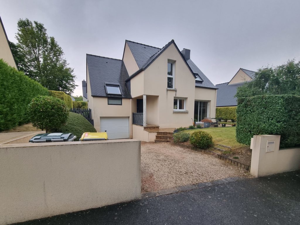 Vue extérieure d’une maison surélevée avec aménagement paysager complet.