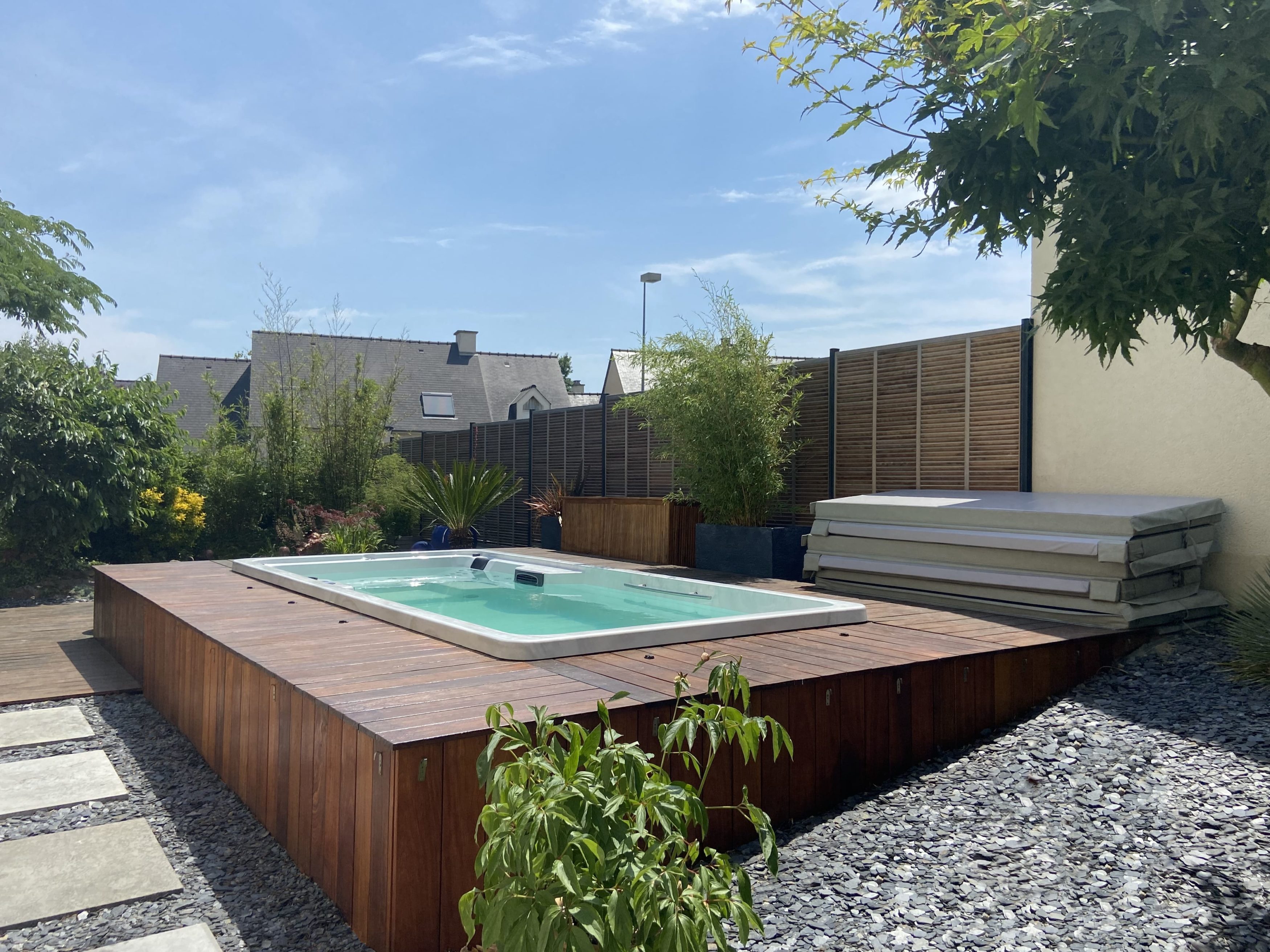 spa de nage avec plage et habillage en bois exotique, allée en pas japonais en granit et massif paillage ardoise